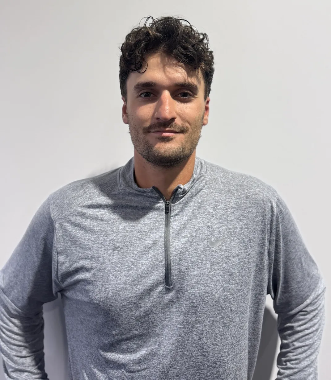 Portrait de Jean-Christophe Masson, en chandail de sport gris, devant un mur clair.