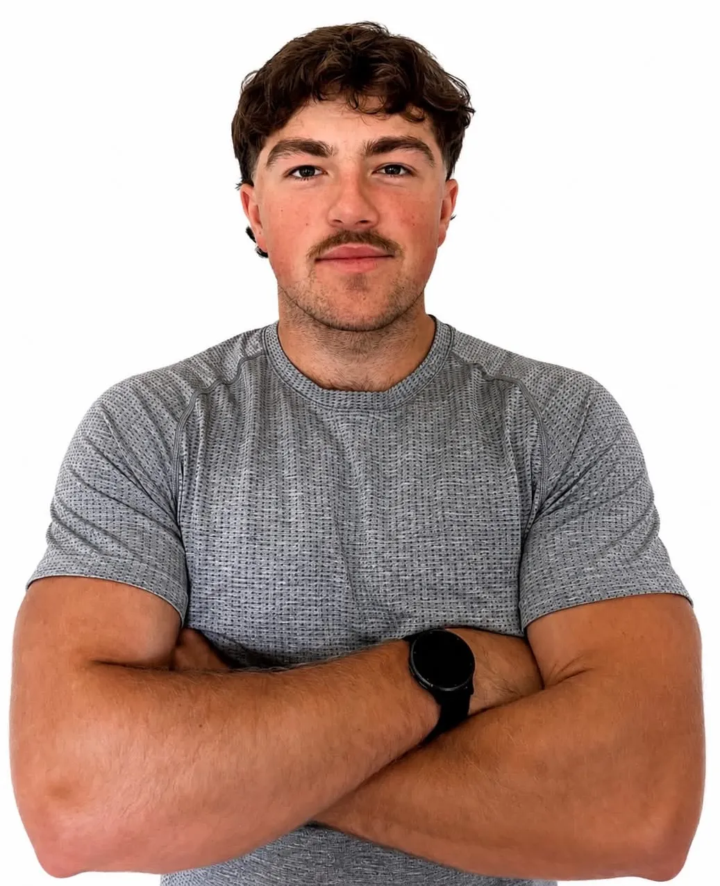 Portrait de Pierre-Luc Jacques, bras croisés, en t-shirt de sport gris sur fond blanc.