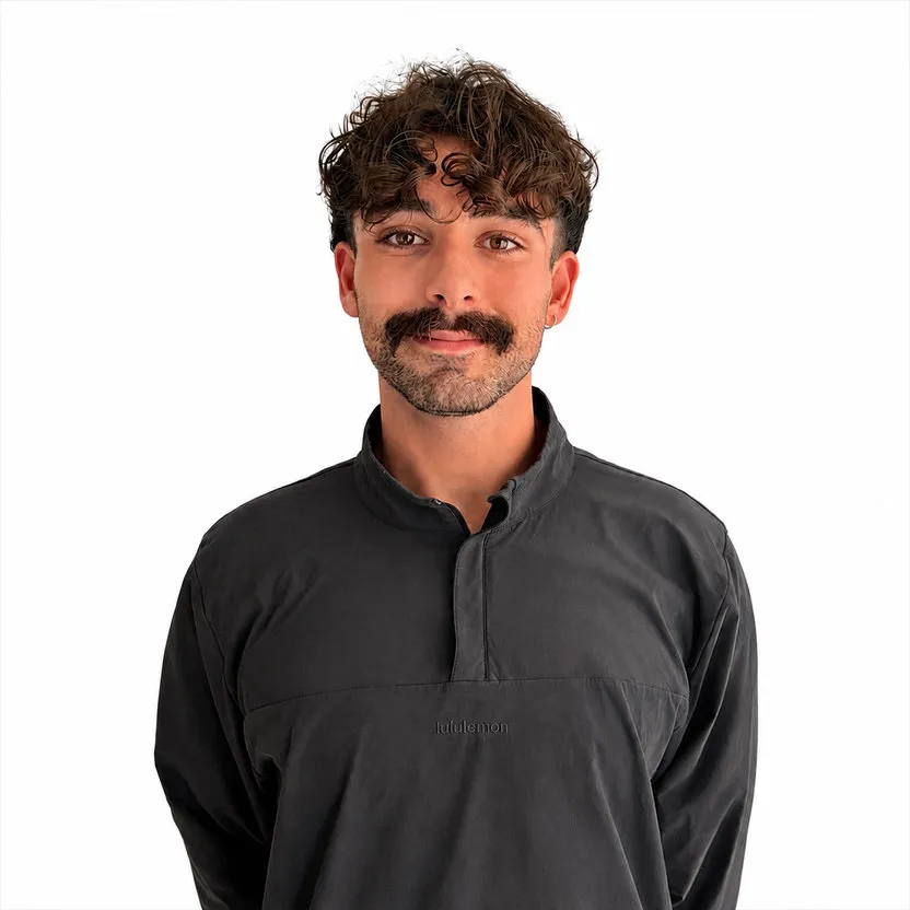 Portrait de Samuel Fortier, souriant, en chandail de sport gris foncé sur fond blanc.
